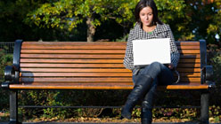 Woman sitting on a bench looking at laptop computer