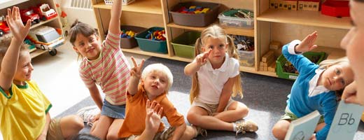 children raising their hands in classroom